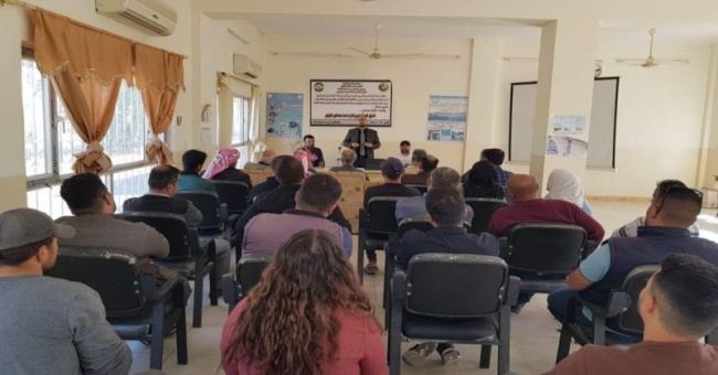 A lecturer  lectures in a field observation on modern methods of managing and serving olive groves.